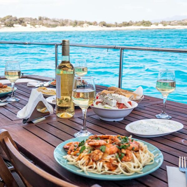 A bottle of wine and plates with food on a table on a yacht in the sea